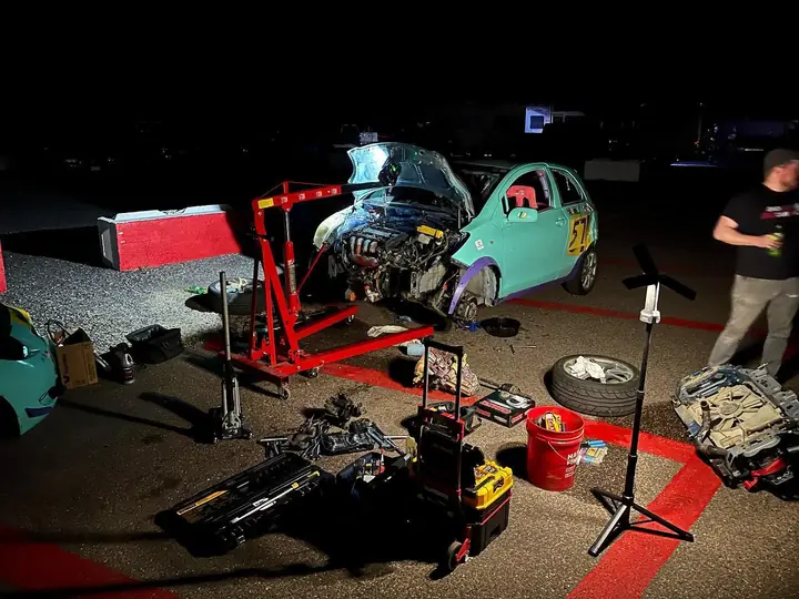 Turquoise Toyota Yaris number 57 raised for nighttime paddock repairs